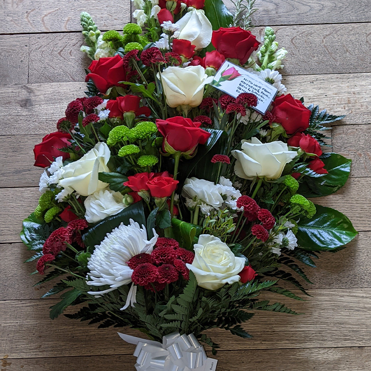 Market Harborough Funeral Flowers, Leicester Tigers Rugby club tribute, Handtied flat sheaf, with red, white & green flowers with bow.