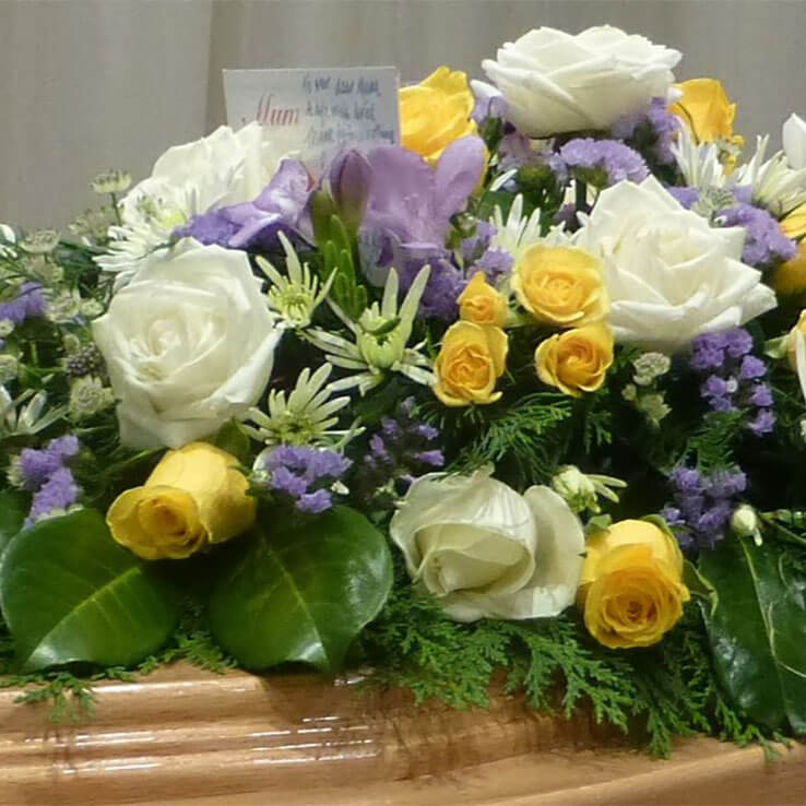 Market Harborough Funeral Flowers, Casket spray with yellow, white and lilac flowers.