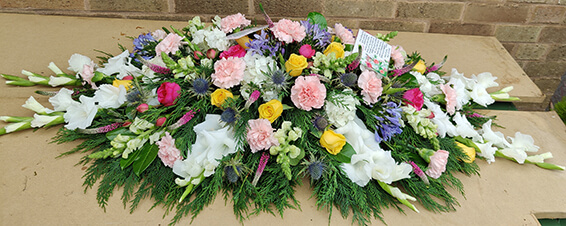 Oadby Funeral Flowers, Wigston Funeral flowers, Leicester funeral flowers, Pink, white, blue and yellow flower Casket spray