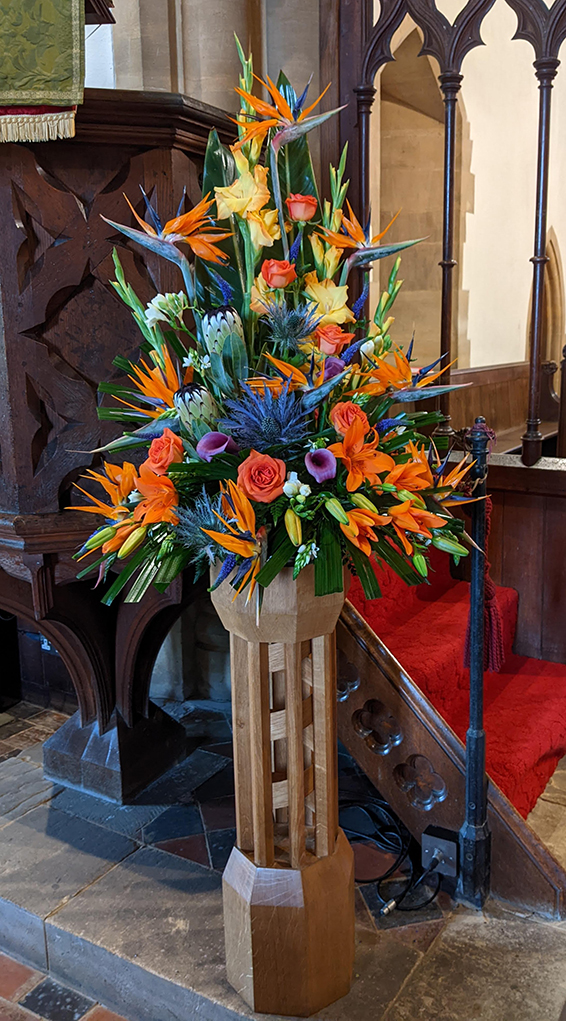 Oadby Funeral Flowers, Wigston Funeral flowers, Market Harborough Funeral Flowers, Grand Pedestal Arrangement, suitable for a church or cathedral, flowers include birds of paradise, orange roses, large eryngium, gladioli & freesia all suppoted with varied greenery.