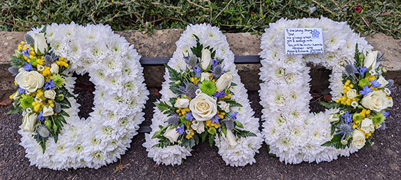 Oadby Funeral flowers, Wigston Funeral Flowers, Market Harborough Funeral Flowers, Leicester Funeral Flowers, DAD tribute, traditional based style with large sprays of whitel, lemon & blue flowers